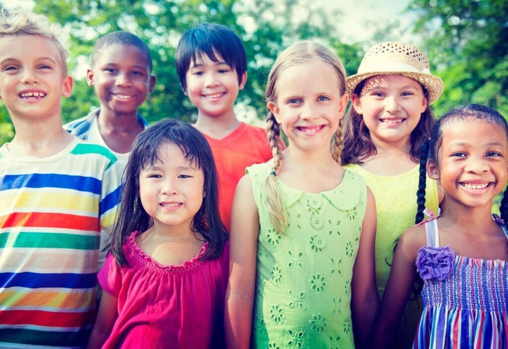 A group of children standing together in front of trees.