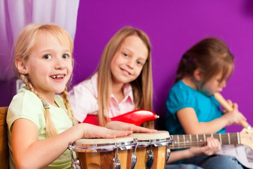 Three children are playing musical instruments together.