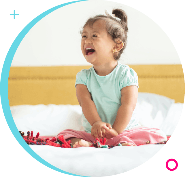 A little girl sitting on the bed laughing.