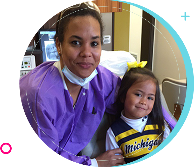 A woman and child in dental office with michigan on the shirt.