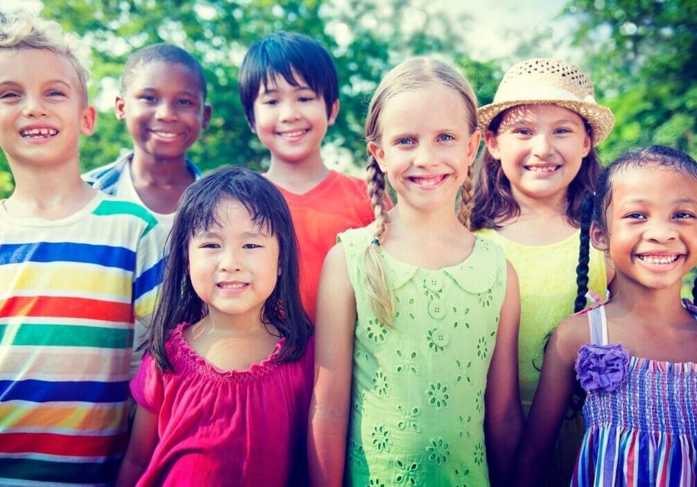 A group of children standing together in front of trees.