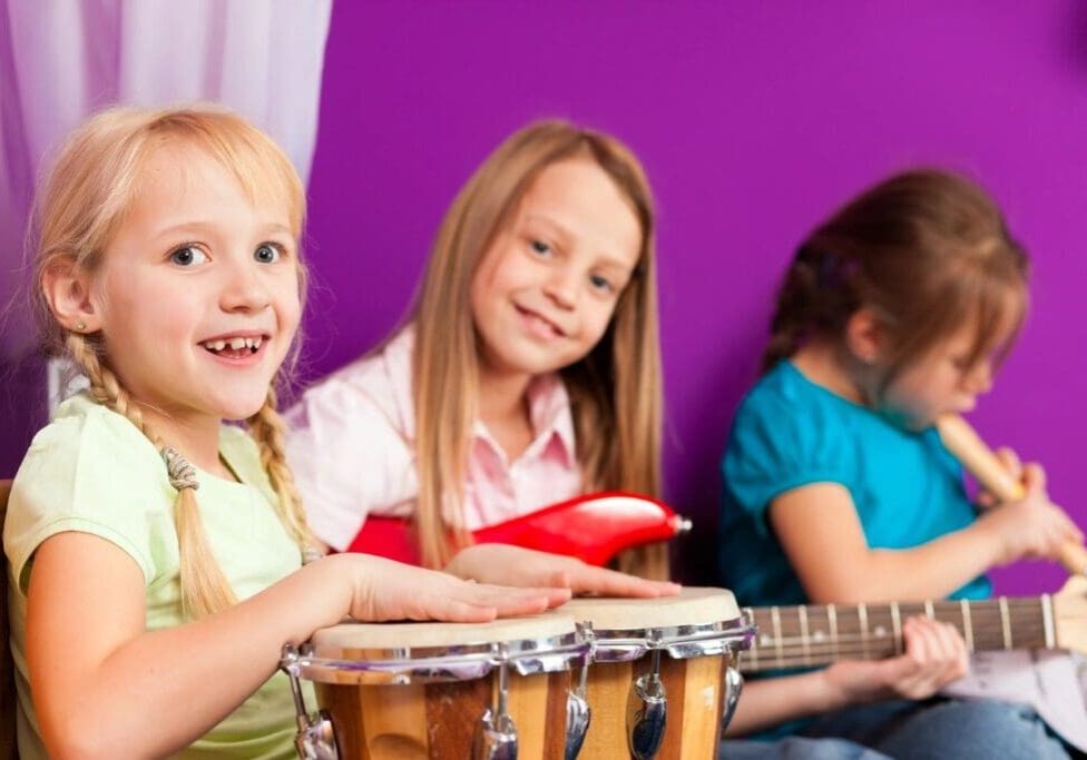 Three children are playing musical instruments together.